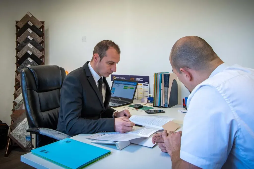 Conseiller funéraire présentant un contrat d'obsèques à un client en agence.